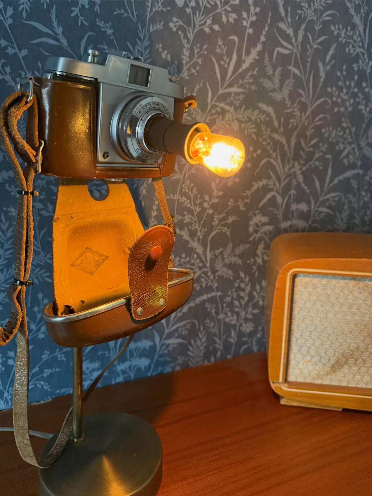 Bordslampa byggd av en gammal kamera i läderfodral, tänd